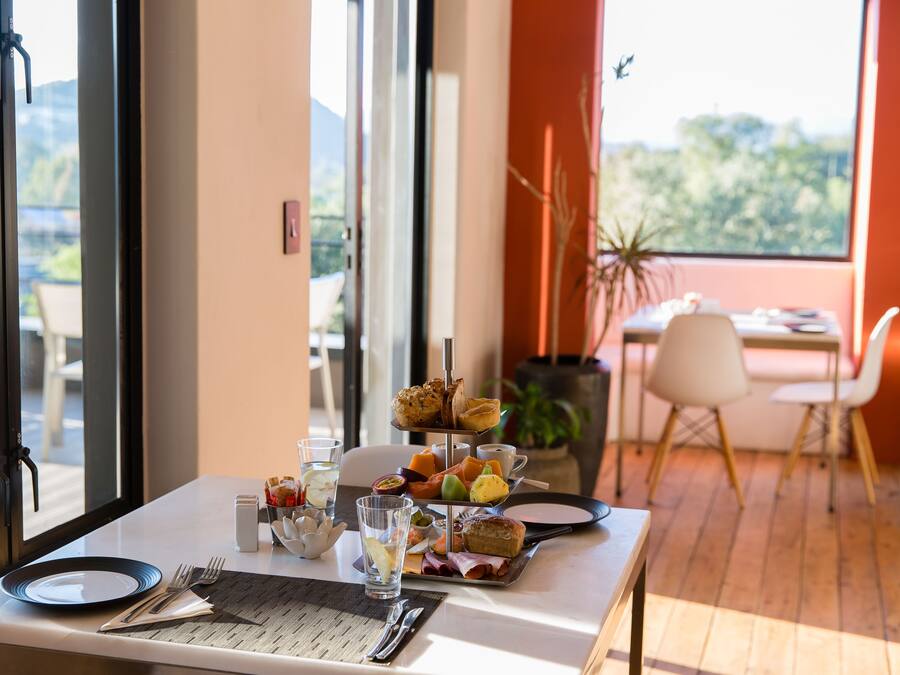 A breakfast table set with plates, cutlery, and a variety of pastries and fruits.