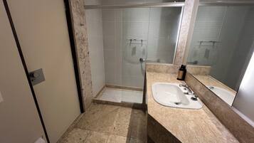Un baño moderno con ducha, lavamanos y un espejo grande.
