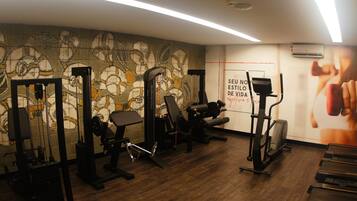 Un gimnasio con equipo de ejercicio, un mural y una cinta de correr.