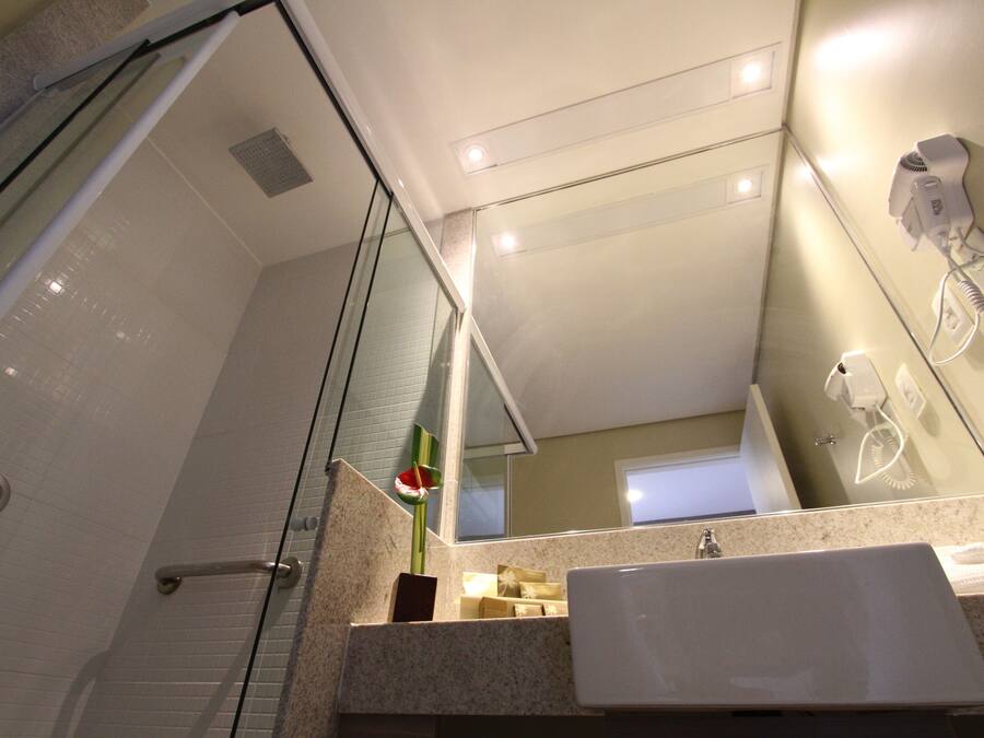 Un baño moderno con cabina de ducha de vidrio, un lavamanos con toalla y un secador de pelo montado en la pared.