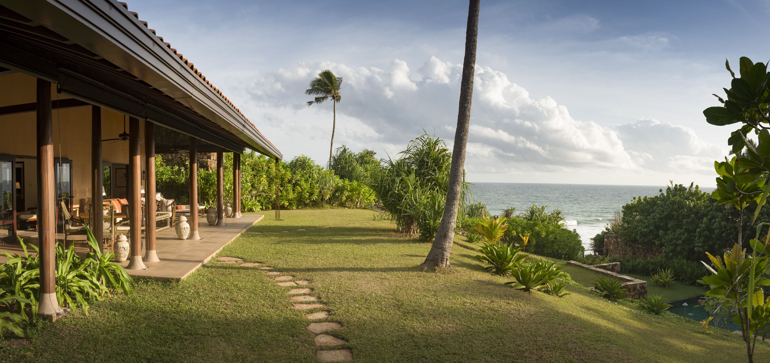 A covered outdoor area with a patio, seating, and a view of the ocean.