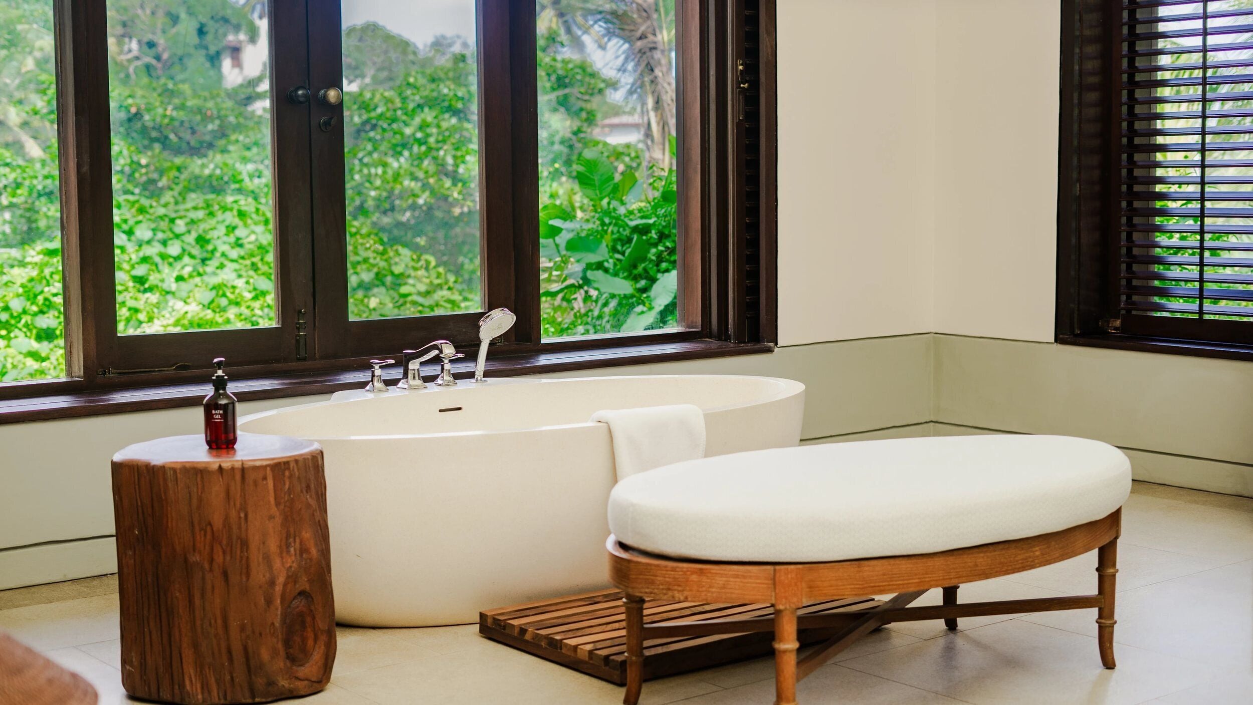 A bathroom with a bathtub, a wooden stool, and a bench.