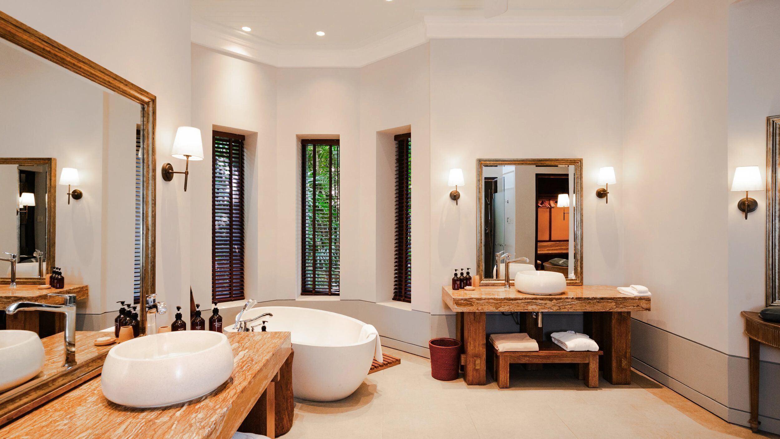 A spacious bathroom with a large bathtub, a wooden vanity with a sink, and a large mirror.