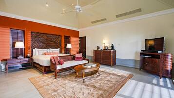 A spacious hotel room with a large bed, a sitting area, a television, and a desk with a lamp.