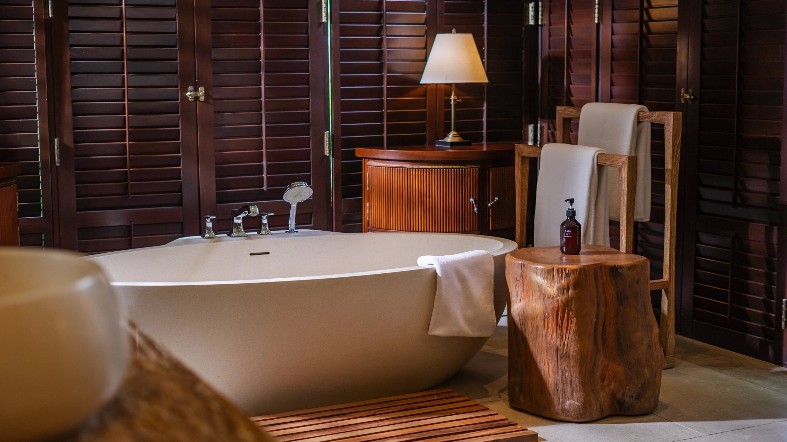 A bathroom with a freestanding bathtub, a wooden vanity, a mirror, and a towel rack.