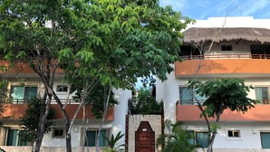 Un edificio con entrada central, varios balcones y follaje circundante.