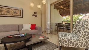 Una sala de estar con sofá, un sillón estampado, una mesa de centro y un comedor con mesa y sillas.