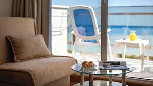 A room with a sofa, a glass table with croissants, a chair, and a view of the sea. - MASLINICA Mimosa Lido Palace Hotel (Labin)