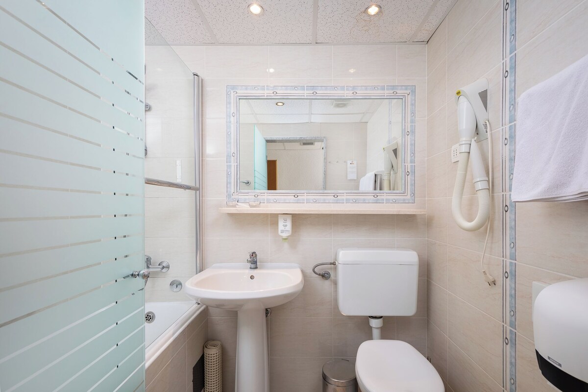 A modern bathroom with a sink, toilet, and a mirror with a vanity.
