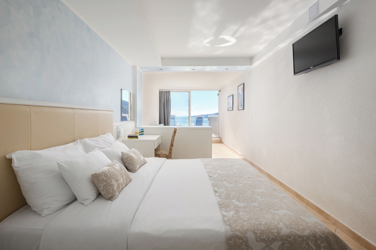 Una habitación de hotel moderna con una cama grande, un escritorio y un televisor montado en la pared.