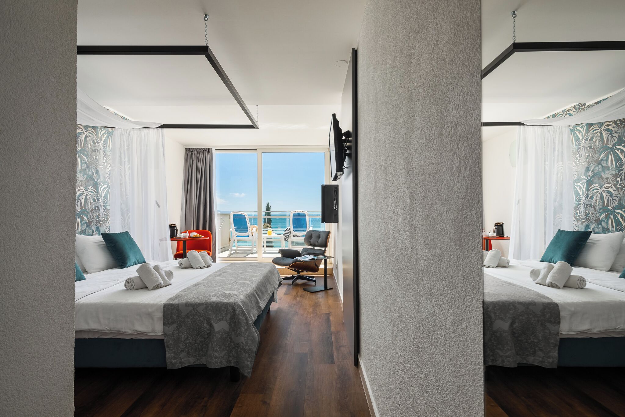 A hotel room with two beds, a balcony with a view, a TV, and a desk.