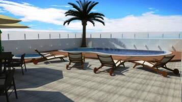 A rooftop lounge area with a pool, lounge chairs, and a palm tree.