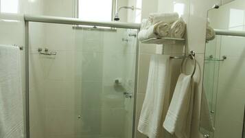 A bathroom with a glass-enclosed shower, a toilet, a granite sink, and a mirror.