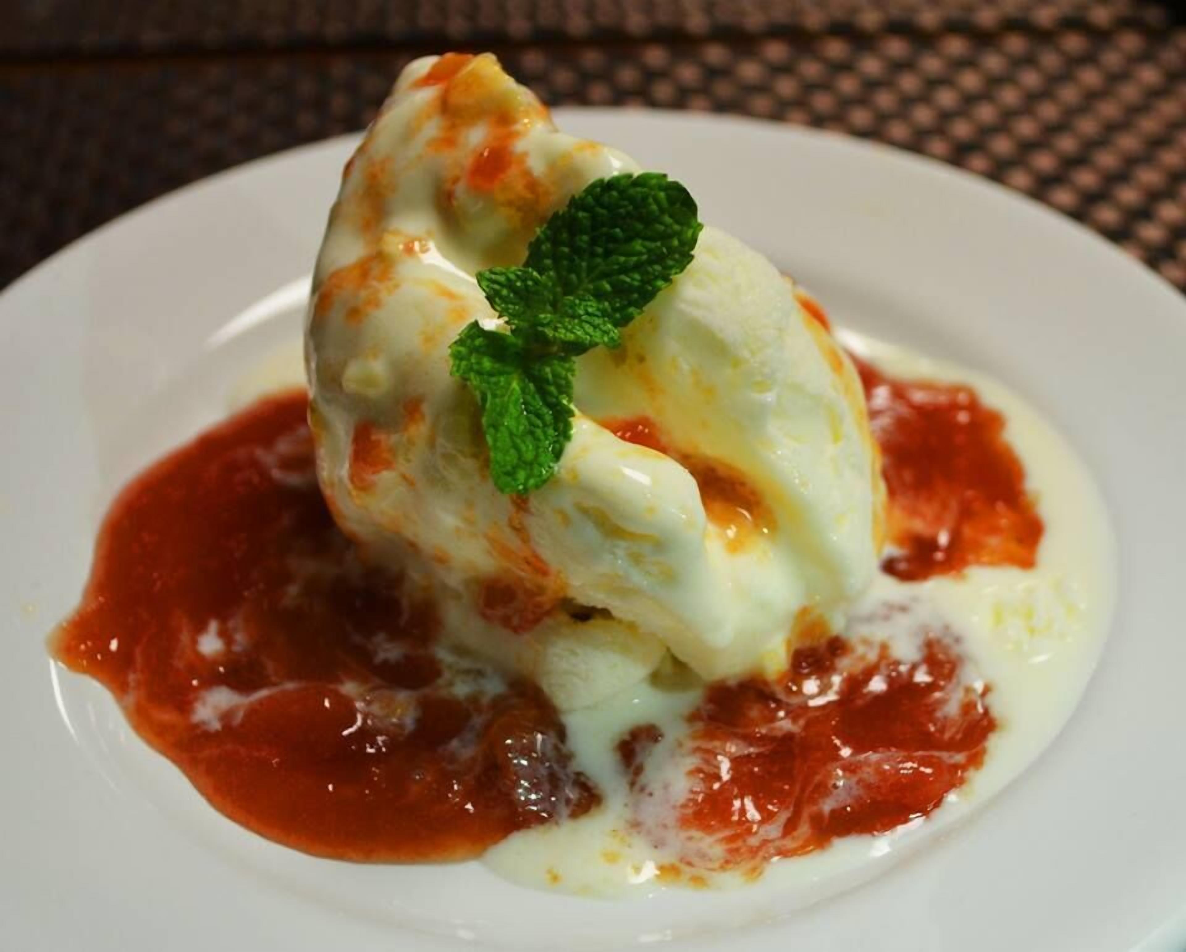 A dessert with a scoop of ice cream on a plate, garnished with a mint leaf.