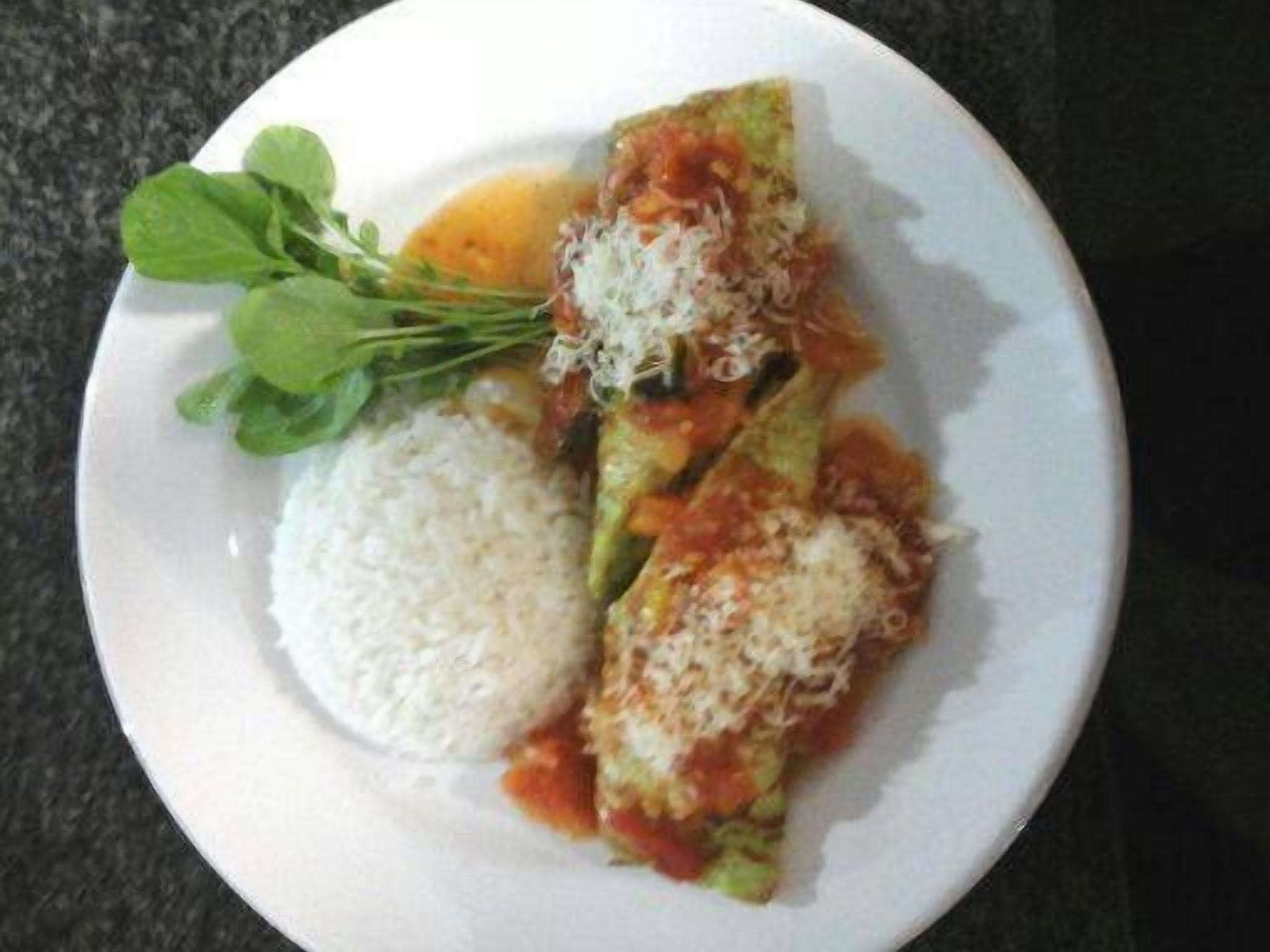 Um prato com abobrinha recheada, acompanhado de arroz e uma pequena salada.