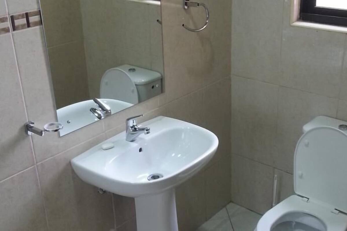 A bathroom with a white sink, a toilet, and a mirror.