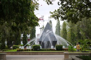 A water fountain with multiple jets in a landscaped area with trees and shrubs. - Hotel Castilla (David)