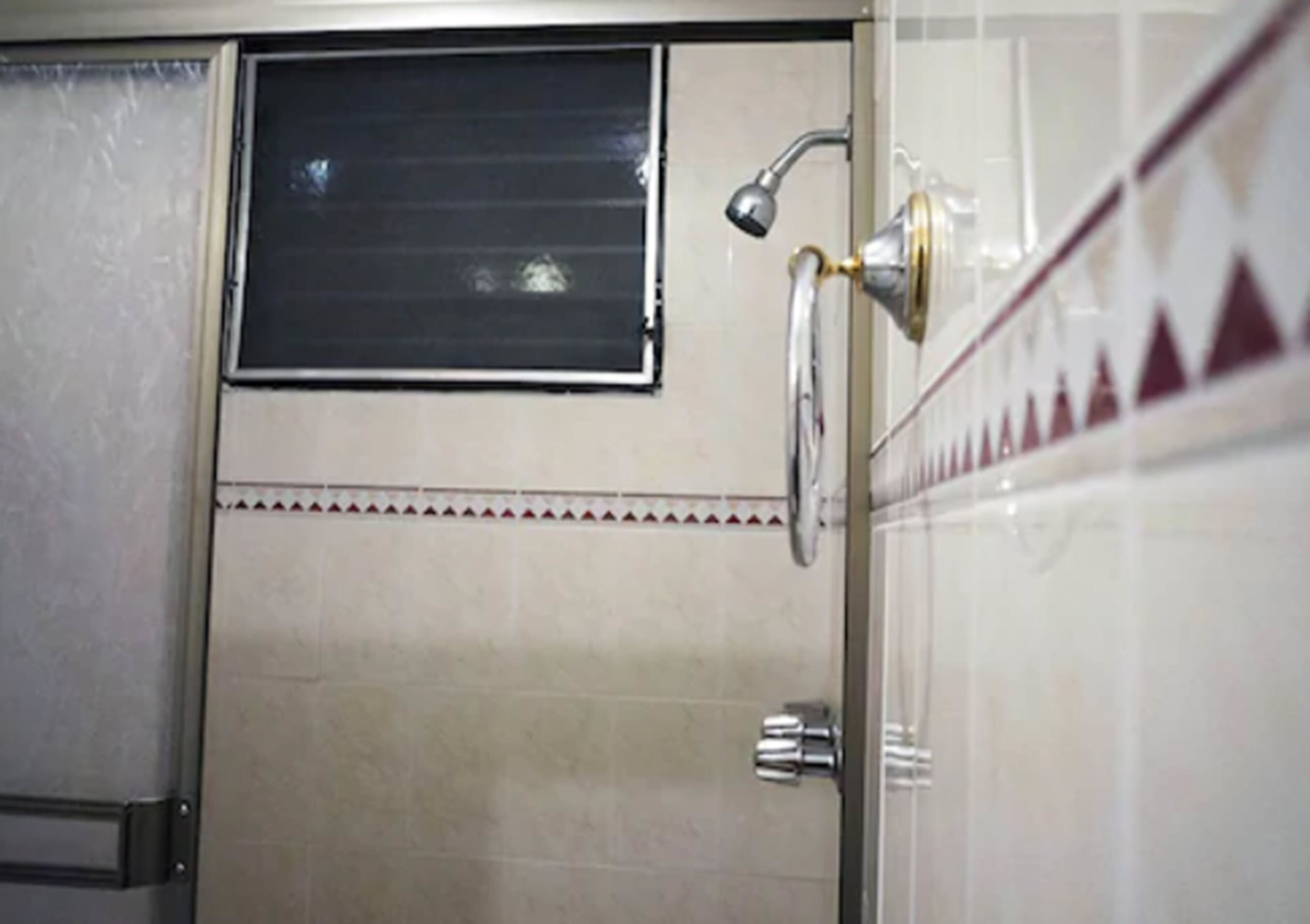 Un baño con ducha, ventana y un perchero para toallas.