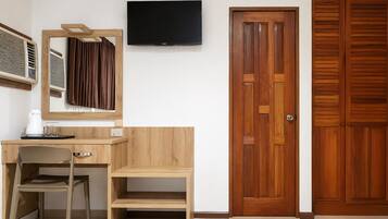 A room with a wooden desk, a chair, a television, and a wooden wardrobe.