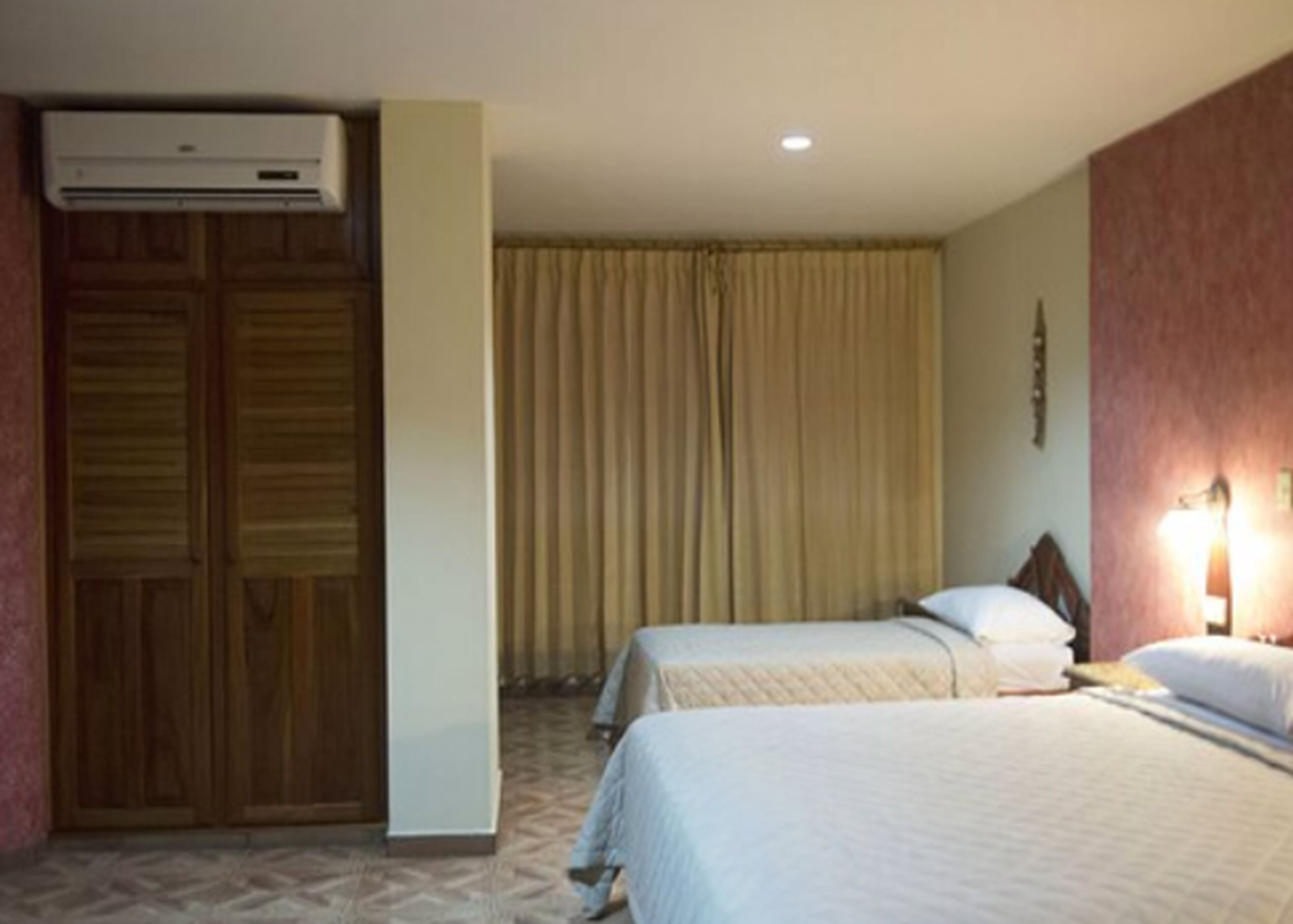 Een hotelkamer met twee bedden, een kledingkast en een airconditioner.