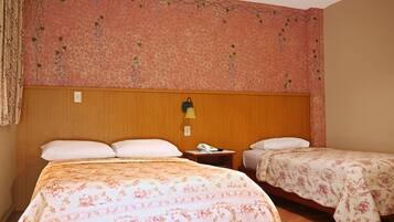 Een hotelkamer met twee bedden, een houten hoofdeinde, een nachtkastje met een lamp en een wand met bloemenprint.