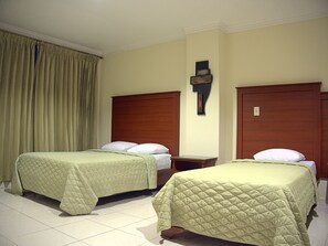 A hotel room with two beds, a wooden headboard, a nightstand, and a wall-mounted light fixture. - Hotel Castilla (David)