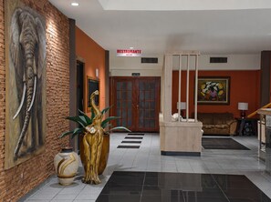 A lobby with a reception desk, a large elephant sculpture, a painting, and a brick wall. - Hotel Castilla (David)