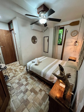 Relax in a tidy room with a comfortable bed, ceiling fan, and air conditioning unit.