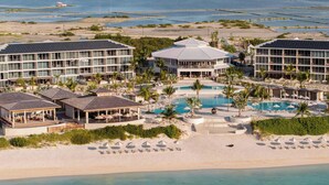 Un complejo turístico con varias edificaciones, una piscina central y zona de playa.