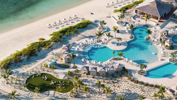 Vista aérea de un resort con múltiples piscinas, una playa y zonas de descanso.