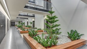 A modern interior with a central planter area, a staircase, and a mezzanine level. - Apartinfo Apartments - Sadowa (Gdansk)