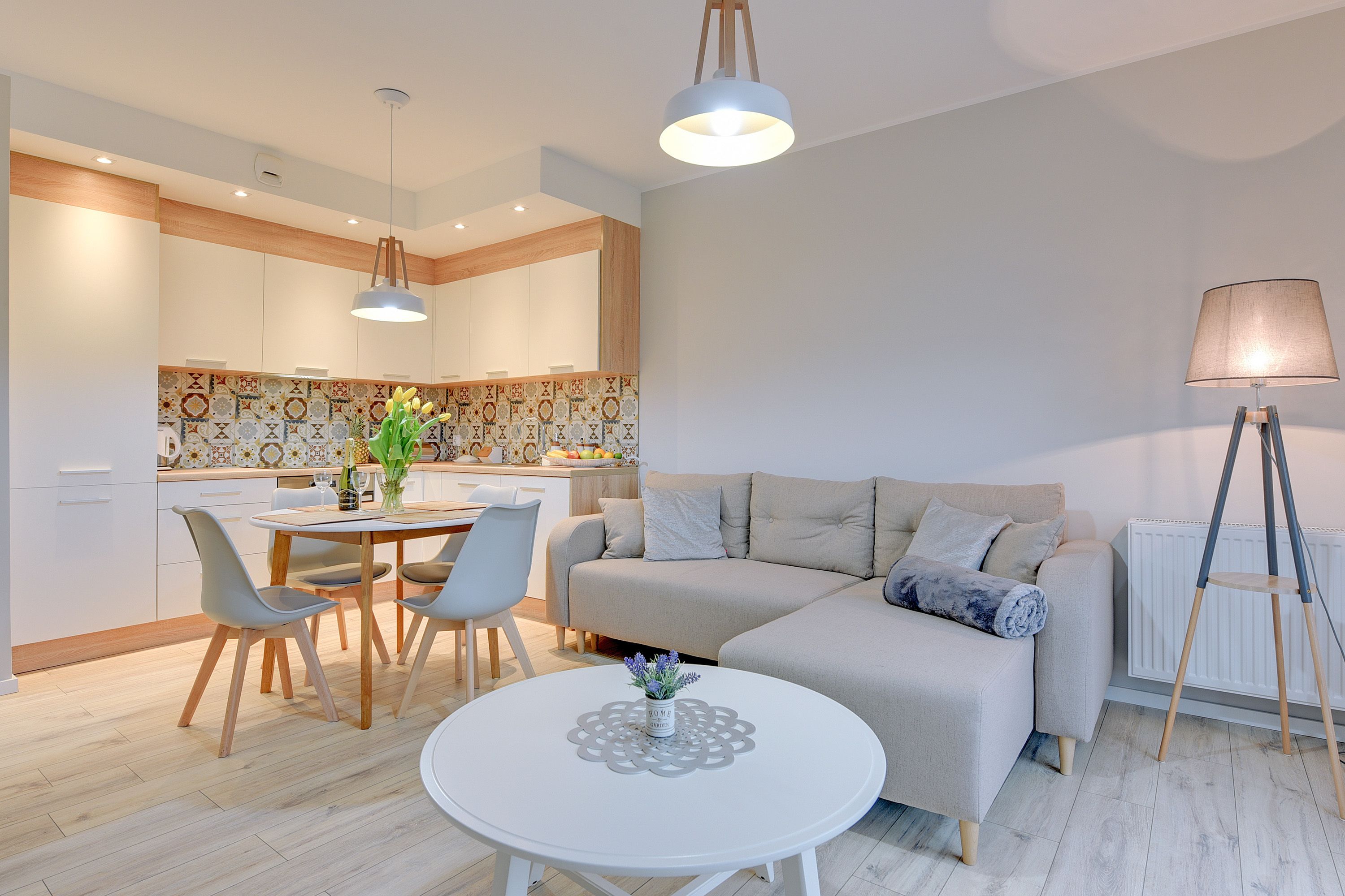 Una sala de estar moderna con un sofá, una mesa de comedor con sillas, una mesa de centro blanca y una lámpara.