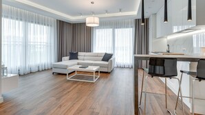 A modern living room with a sectional sofa, a coffee table, and a bar area with stools. - Apartinfo Island Apartments (Gdansk)