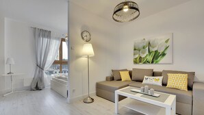 A modern living room with a sofa, a coffee table, a floor lamp, and a painting of tulips on the wall. - Apartinfo Island Apartments (Gdansk)