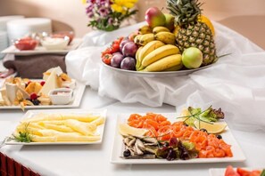 Una mesa de buffet con diversas opciones de comida, como frutas, quesos y ensaladas.