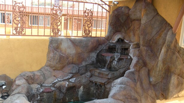 A rock garden with a water feature, including a small waterfall and a pond. - Trails Motel (Lone Pine)