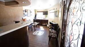 A spacious living area with a kitchen, a dining table, and a sofa. - Trails Motel (Lone Pine)