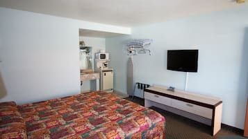 Ein Hotelzimmer mit einem Bett, einem Schreibtisch, einem Fernseher und einer kleinen Küchenzeile.