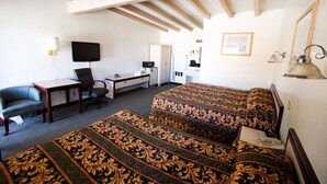 A hotel room with a bed, a desk, a chair, a television, and a lamp. - Trails Motel (Lone Pine)