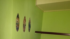 Una habitación con una pared verde, tres adornos colgados en la pared y dos estantes vacíos.