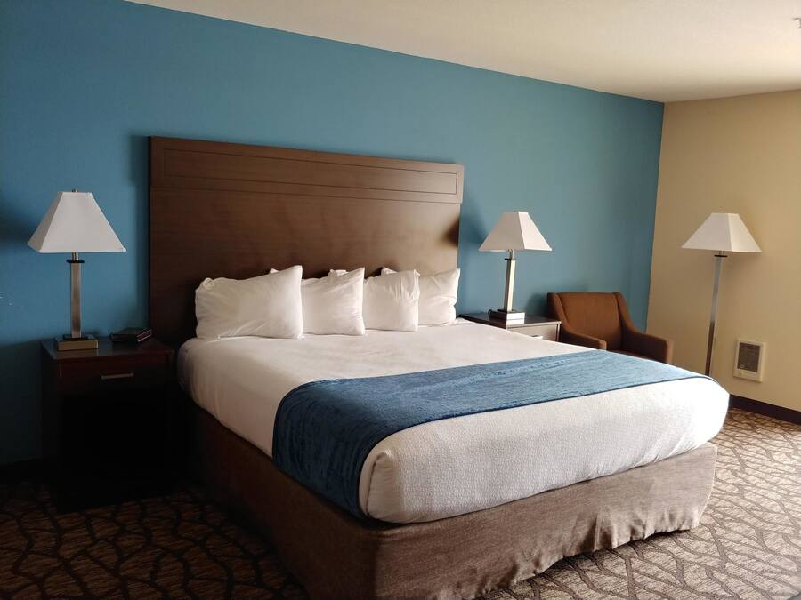 Quarto de hotel com uma cama grande, duas mesas de cabeceira e duas luminárias.