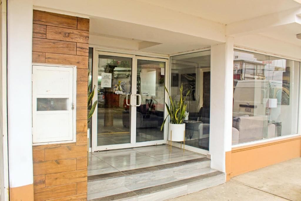 Entrada de hotel com parede de madeira, porta de vidro e planta em vaso.