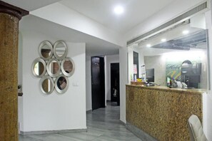 A hotel reception area with a granite counter, a wall-mounted mirror arrangement, and a reception desk. - Hotel Villa Margaritas (Villahermosa)