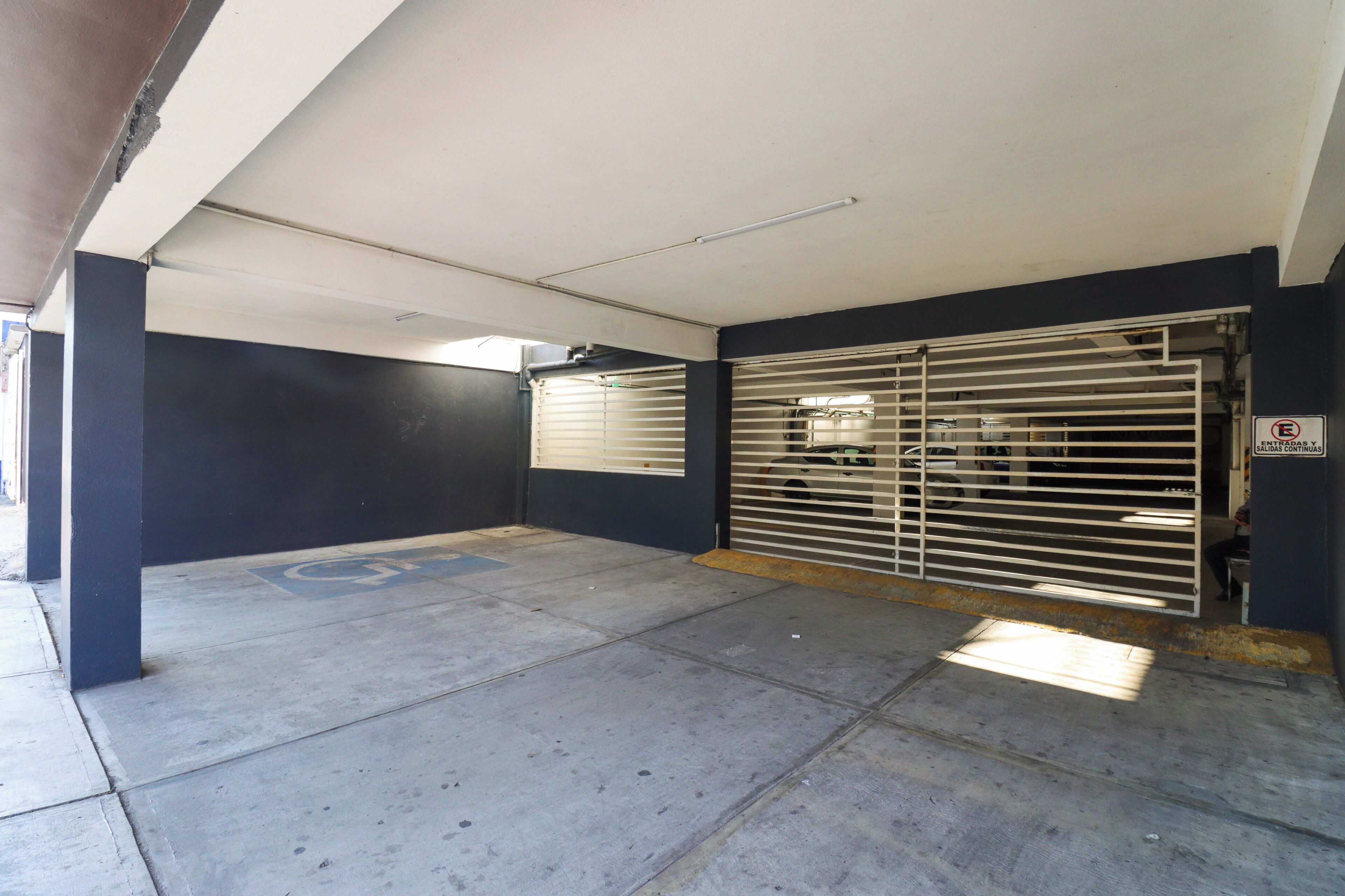 A parking garage with a disabled parking space marked by a wheelchair symbol.