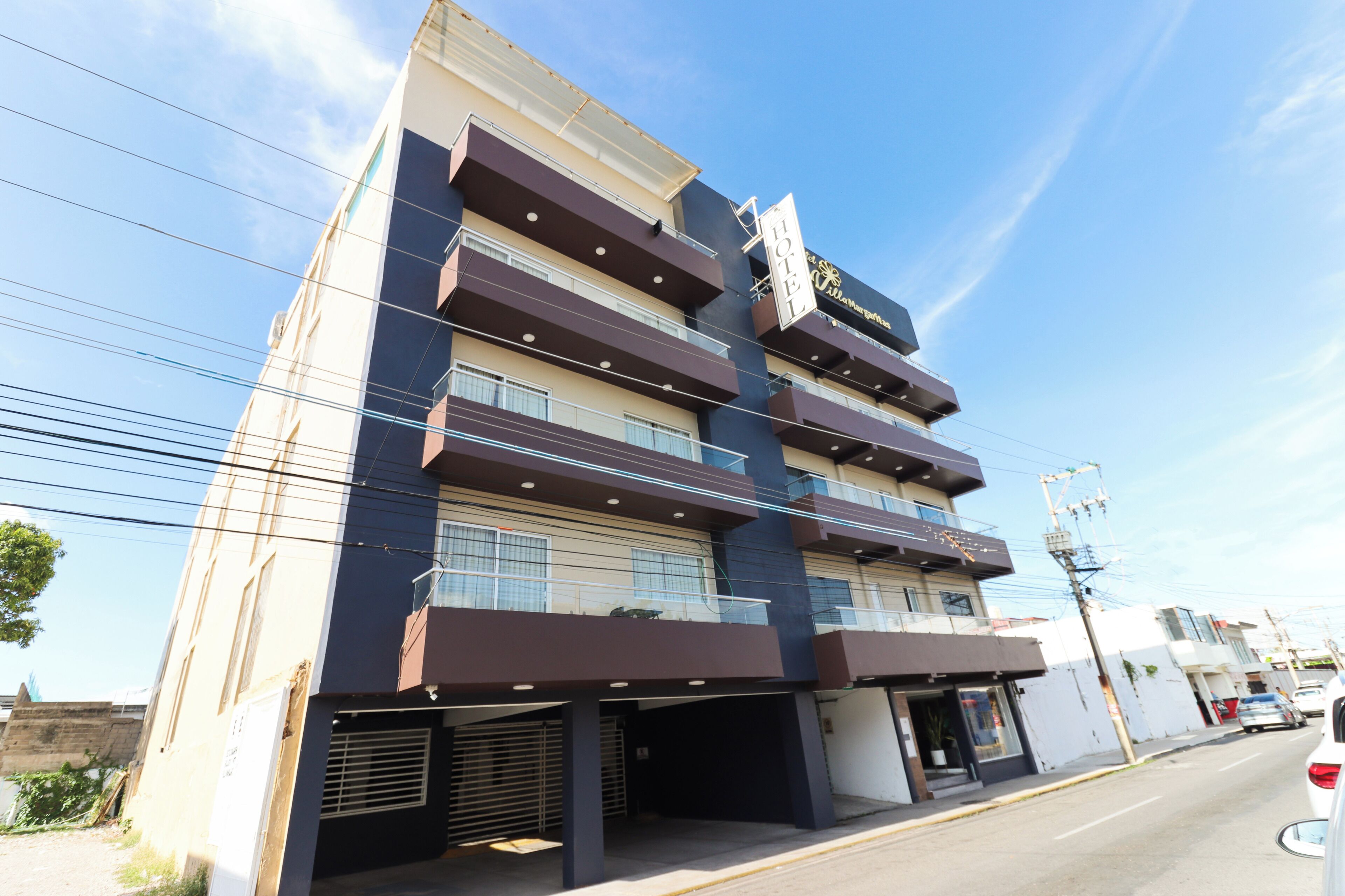 A multi-story hotel with a modern design, featuring balconies and a prominent sign.