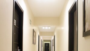 A long, narrow hotel corridor with doors on both sides, a tiled floor, and a ceiling light. - Hotel Villa Margaritas (Villahermosa)