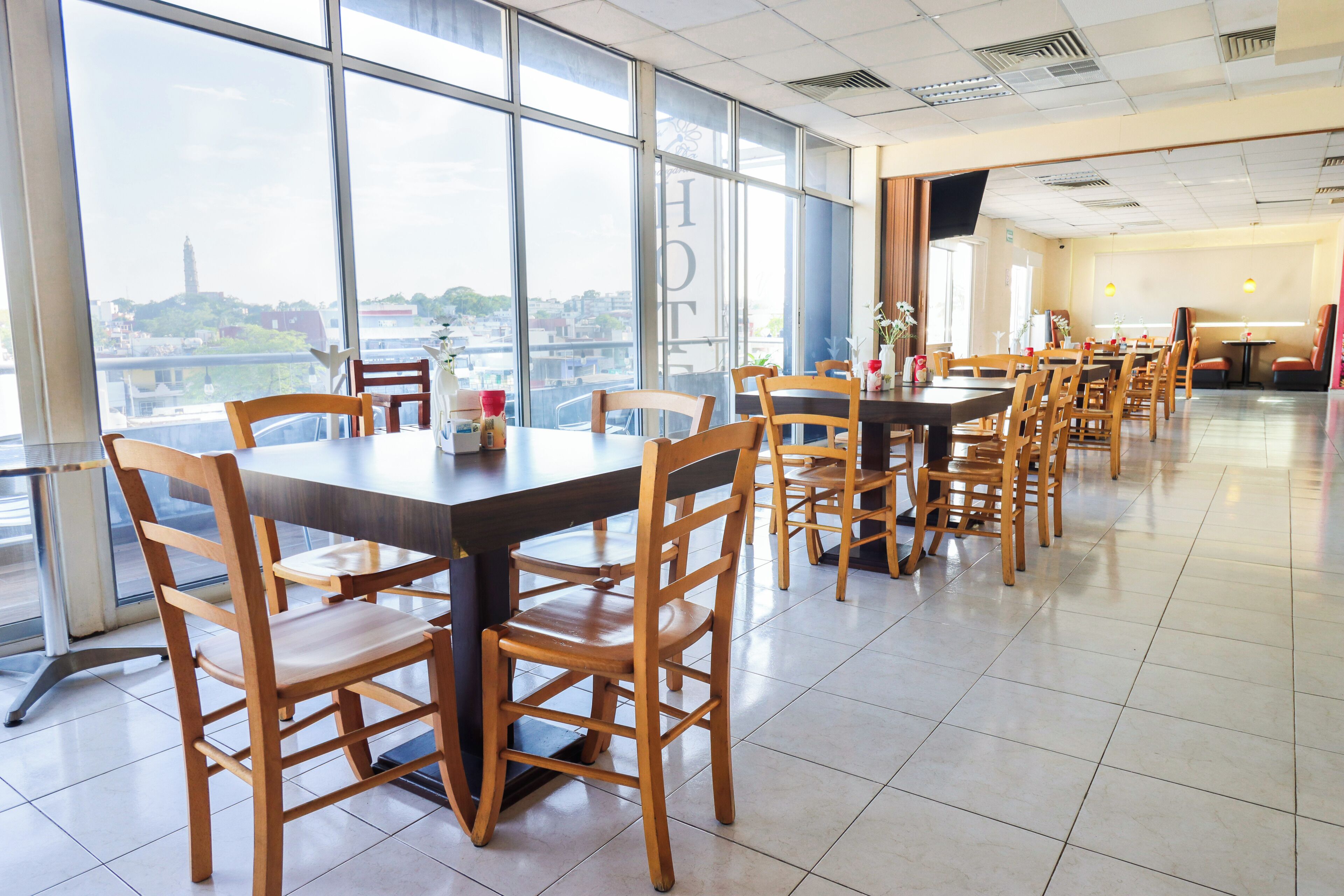 A spacious dining area with high tables and chairs, large windows offering a city view, and a clean, modern interior design.