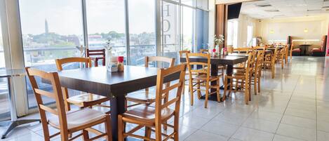 A spacious dining area with high tables and chairs, large windows offering a city view, and a clean, modern interior design.