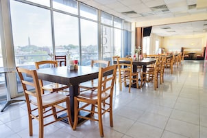 Un amplio comedor con mesas y sillas altas, grandes ventanales con vistas a la ciudad y un diseño interior moderno y limpio.