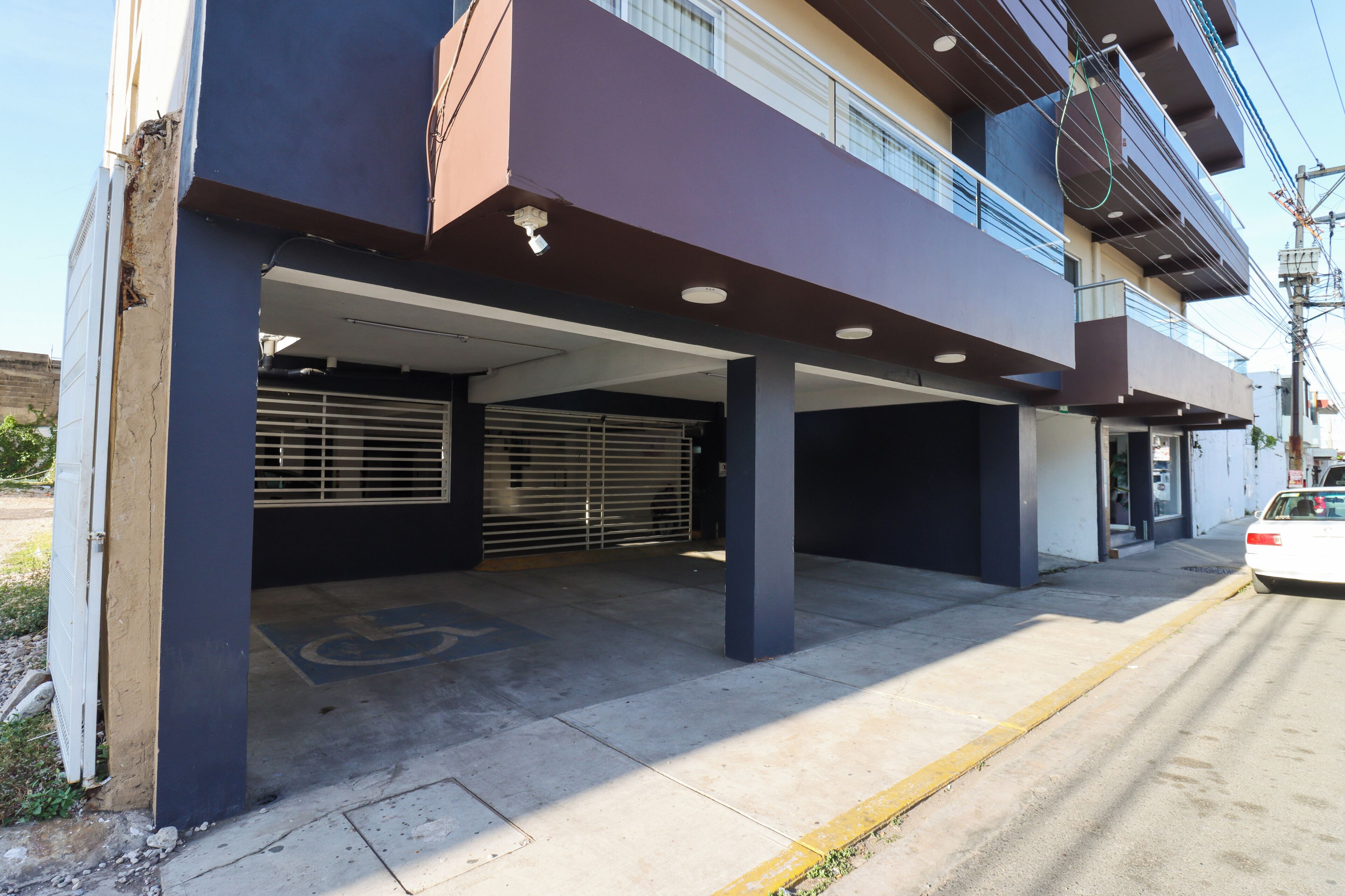 A parking garage with multiple levels, concrete pillars, and a disabled parking space.